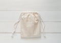 Canvas bag with drawstring, mockup of small eco sack made from natural cotton fabric cloth flat lay on white wood background Royalty Free Stock Photo