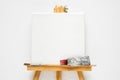 Canvas on easel, paint tube and paintbrush. White canvas backgr