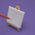 Canvas easel with canvas and pencil for drawing on a purple background. Minimal painting scenes