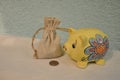 Bag full of money and yellow piggy bank or money box  over blue wooden background. Royalty Free Stock Photo