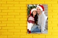 Canvas with printed photo happy couple wearing Santa hats on yellow brick wall, space for text Royalty Free Stock Photo