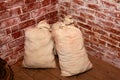 canvas sacks of grain in the corner of antique kitchen. background red brick wall Royalty Free Stock Photo