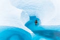 Canyoneering in a boat on a glacier, a young man paddles through a narrow section of blue water surrounded by walls of ice