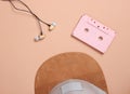 Cap, audio casset earphones on a brown background, music lover, minimalism, top view. Royalty Free Stock Photo