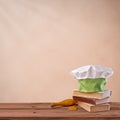 Cap chef, cookbook and kitchenware on beige vintage background