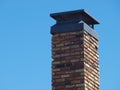 A Brick Chimney on a Blue Sky with a Sturdy Cap