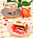 Cap of coffee, a rose and a cake on tablecloth Royalty Free Stock Photo