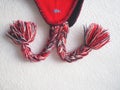 Cap with earflaps in the Norwegian style. Knitted fashion item with ties and pom-pom tassels. Red yarn with black and Royalty Free Stock Photo