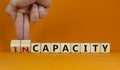 Capacity or incapacity symbol. Businessman turns wooden cubes and changes the word `incapacity` to `capacity`. Beautiful orang