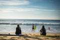 Capbreton, France - October 4, 2017: back view of women girls surfers sitting on sandy beach on surfboard