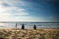 Capbreton, France - October 4, 2017: back view of women girls surfers sitting on sandy beach on surfboard