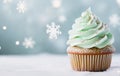 Capcake decorated with pastel green cream on a beautiful winter snowflakes blurred background. Christmas dessert food on the table