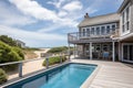 cape cod house with private beach access, view of the ocean, and swimming pool