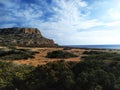 Cape Greco near Ayia Napa. Mediterranean Sea coast, Cyprus. Red brown soil with green bushes near Cavo Greco.