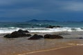 Cape Hawke in the distance with a breaking wave and rocks foreground Royalty Free Stock Photo