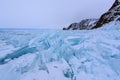 Cape Hoboy in Olkhon island covered with icicles in sunny march day. Lake Baikal with cloudy sky and big blocks of blue Royalty Free Stock Photo