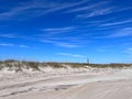 The Cape Lookout, North Carolina lighthouse in the distance from the beach under a blue sky with white clouds Royalty Free Stock Photo