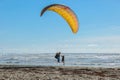 A skydiver landing on a beach of Oregon coast greeted by a random person