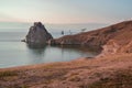 Cape Shamanka rock in clear blue Lake Baikal among grassy steppe, mountains, warm sunset Royalty Free Stock Photo