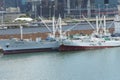 White refrigerated cargo ship and fishing vessel moored side by side in port.