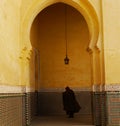 Caped figure seen through archway in Meknes, Morocco Royalty Free Stock Photo