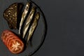 Capelin fish of cold smoked on round slate plate on black background.