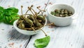 Capers. Marinated or pickled canned capers fruit with fresh rosemary in a small bowl, on gray background. place for text Royalty Free Stock Photo