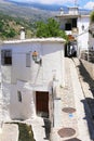 Capileira, Andalusia, Spain - May 29, 2019: narrow paved street with a depression for a mountain stream, white houses decorated
