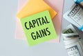 Capital Gains Text on Green Sticker attached to notepad with money dollars Royalty Free Stock Photo