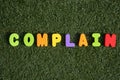 Capital letter `Complain` word from colorful of wood on grass background.