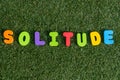 Capital letter `Solitude` word from colorful of wood on grass background.