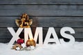 Capital letters forming the word xmas golden putto figurine and christmas cookies on pile of snow against wooden wall Royalty Free Stock Photo