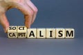 Capitalism or socialism. Hand turns cubes and changes word `capitalism` to `socialism`. Beautiful white background, copy space Royalty Free Stock Photo