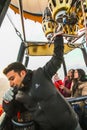 A hot air balloon pilot with one hand on walkie-talkie and the other on the burner