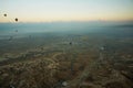 Cappadocia, Turkey: Top view early in the morning from the balloon, misty landscape with fog with mountains and colorful balloons