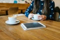 Cappuccino coffee in a mug on the table next to the tablet. Relaxing or meeting in a cafe. The girl is waiting for