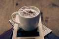 cappuccino coffee on top of a small tower made up of books inside a hipster room