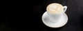 Cappuccino coffee in a white cup on black background. Copy space banner, coffee time