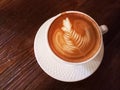 Cappuccino coffee in white cup on dark wood table