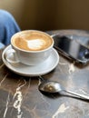 Cappuccino coffee in white cup on marble table with spoon. Royalty Free Stock Photo