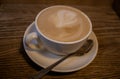 Cappuccino coffee in white cup with saucer and spoon