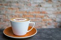 Cappuccino coffee in white cup on wooden table with old brick wa Royalty Free Stock Photo