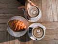 Cappuccino and croissant on the table in the cafe. Delicious breakfast. Womens hands hold a cup of Cappuccino Royalty Free Stock Photo