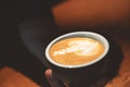 Cappuccino cup with coffee milk design in man`s hands close up