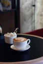 Cappuccino cup of coffee with sugar on the table in restaurant side view and a lot of copy space. Coffee cup latte and saucer.