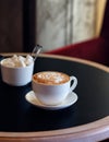 Cappuccino cup of coffee with sugar on the table in restaurant side view and a lot of copy space. Coffee cup latte and saucer. Royalty Free Stock Photo