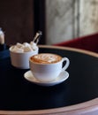 Cappuccino cup of coffee with sugar on the table in restaurant side view and a lot of copy space. Coffee cup latte and saucer. Royalty Free Stock Photo