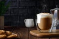 cappuccino in cup and geyser coffee maker on wooden table with black brick wall as background Royalty Free Stock Photo