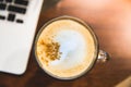 Cappuccino cup and laptop on wooden table. Royalty Free Stock Photo