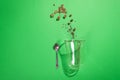 Cappuccino glass cup with sugar and coffee beans on green background with deep shadows, flat lay